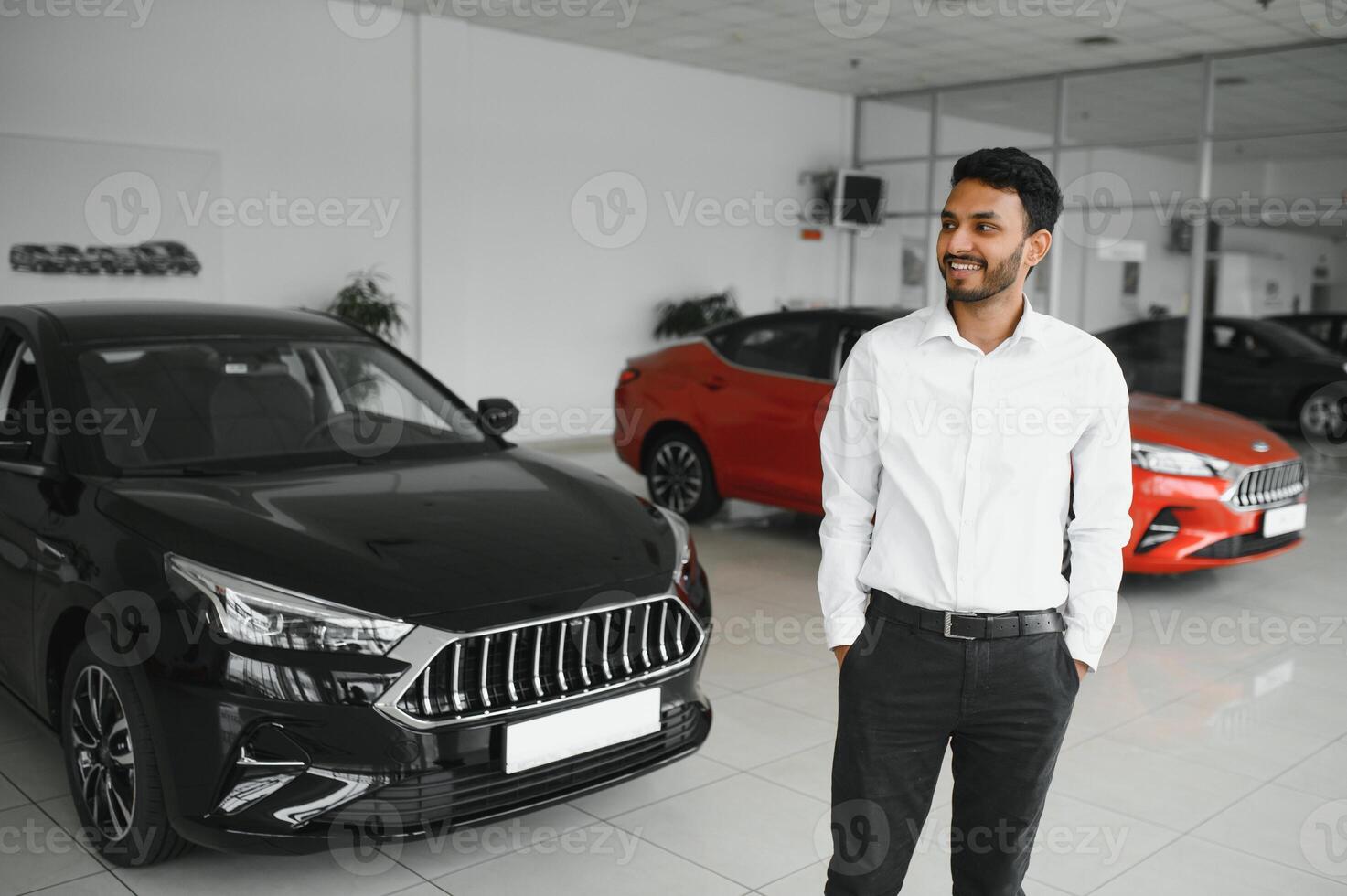 Smiling, friendly indian car seller standing in car salon. photo