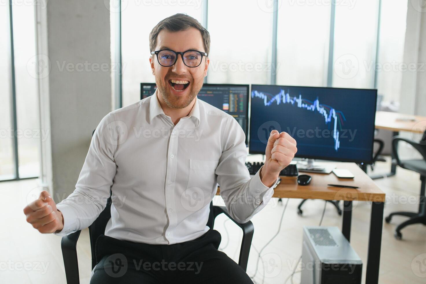 Young bearded man trader at office sitting at table looking camera smiling cheerful photo