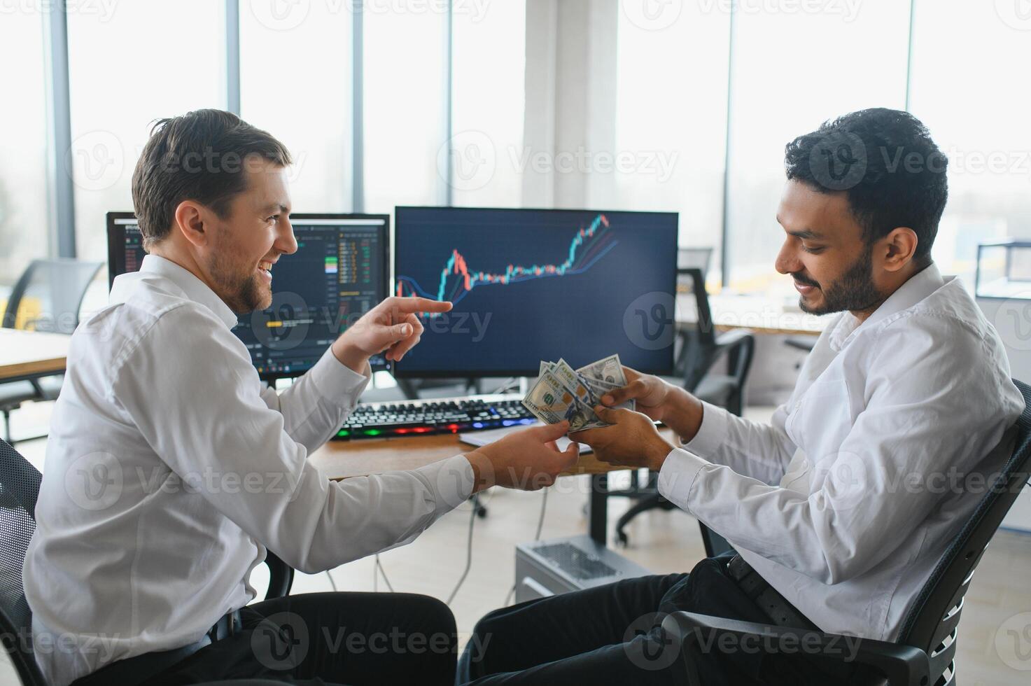 Two successful trader sitting in office and looking at screen, checking cryptocurrency information data on finance market graph, pointing on monitor photo
