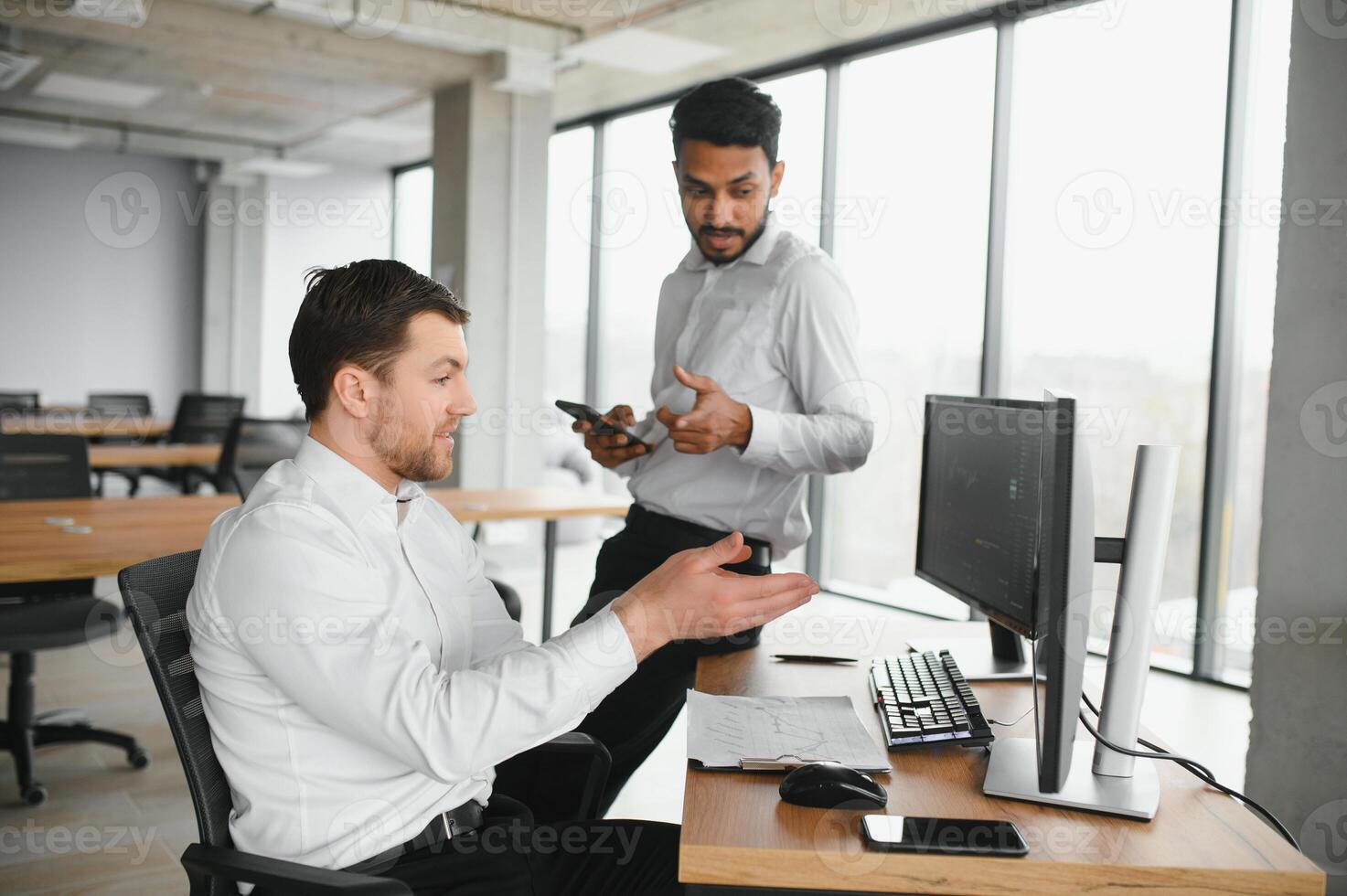 Two successful trader sitting in office and looking at screen, checking cryptocurrency information data on finance market graph, pointing on monitor photo