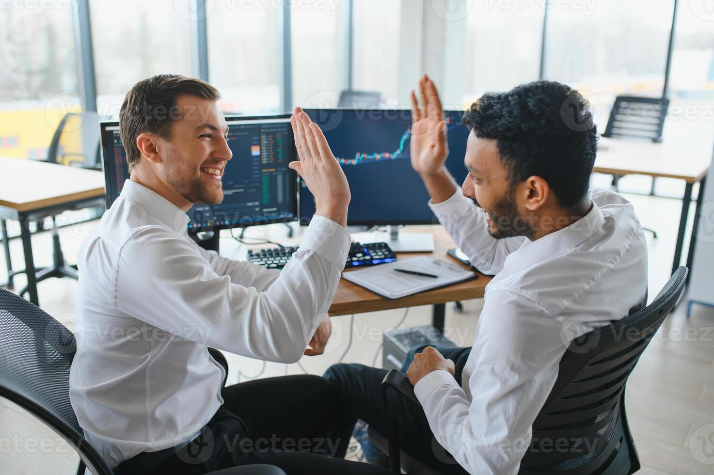 Two successful trader in formalwear pointing at display, analyzing stat and dynamic on forex charts, working in office together photo