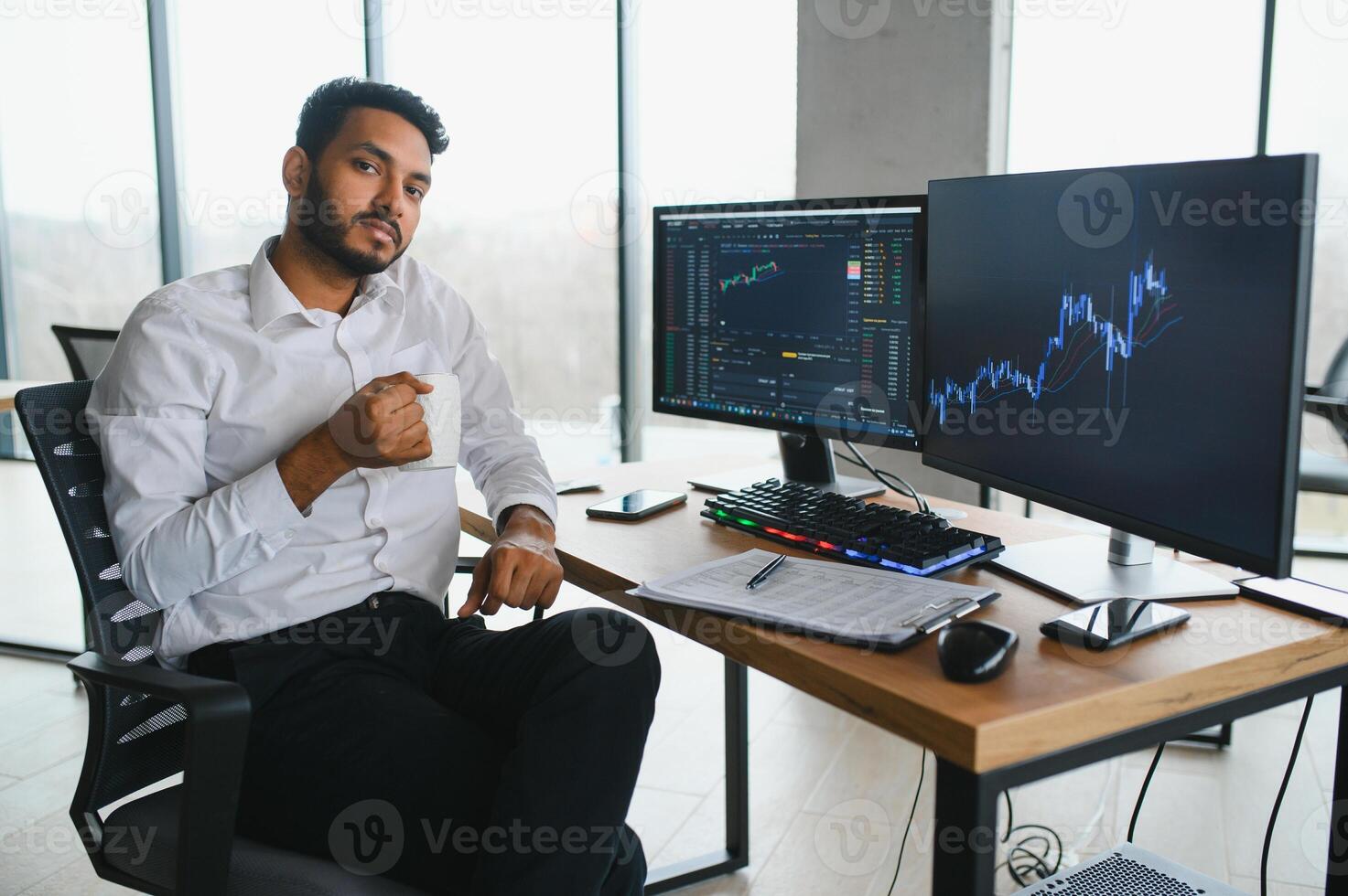 Thoughtful concentrated indian business man entrepreneur investor manager using computer, watching webinar working in office analyzing online data market thinking doing web research looking at laptop. photo