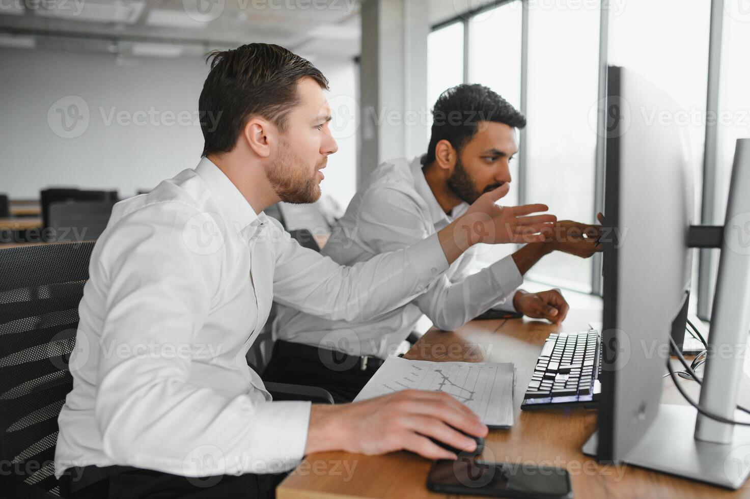 Two successful trader sitting in office and looking at screen, checking cryptocurrency information data on finance market graph, pointing on monitor photo