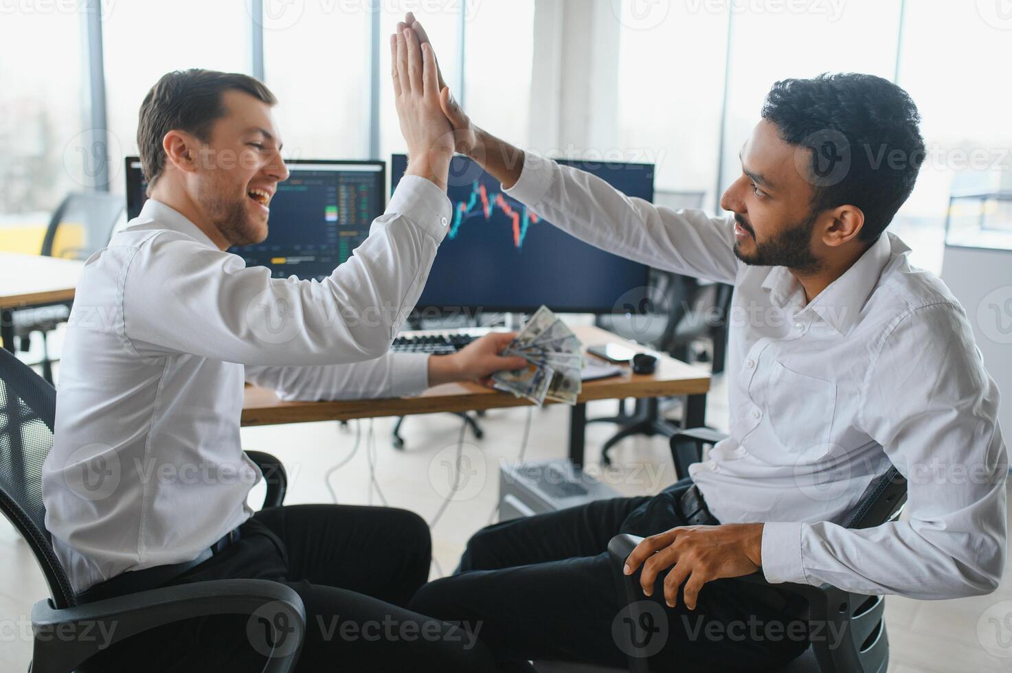 Two successful trader sitting in office and looking at screen, checking cryptocurrency information data on finance market graph, pointing on monitor photo