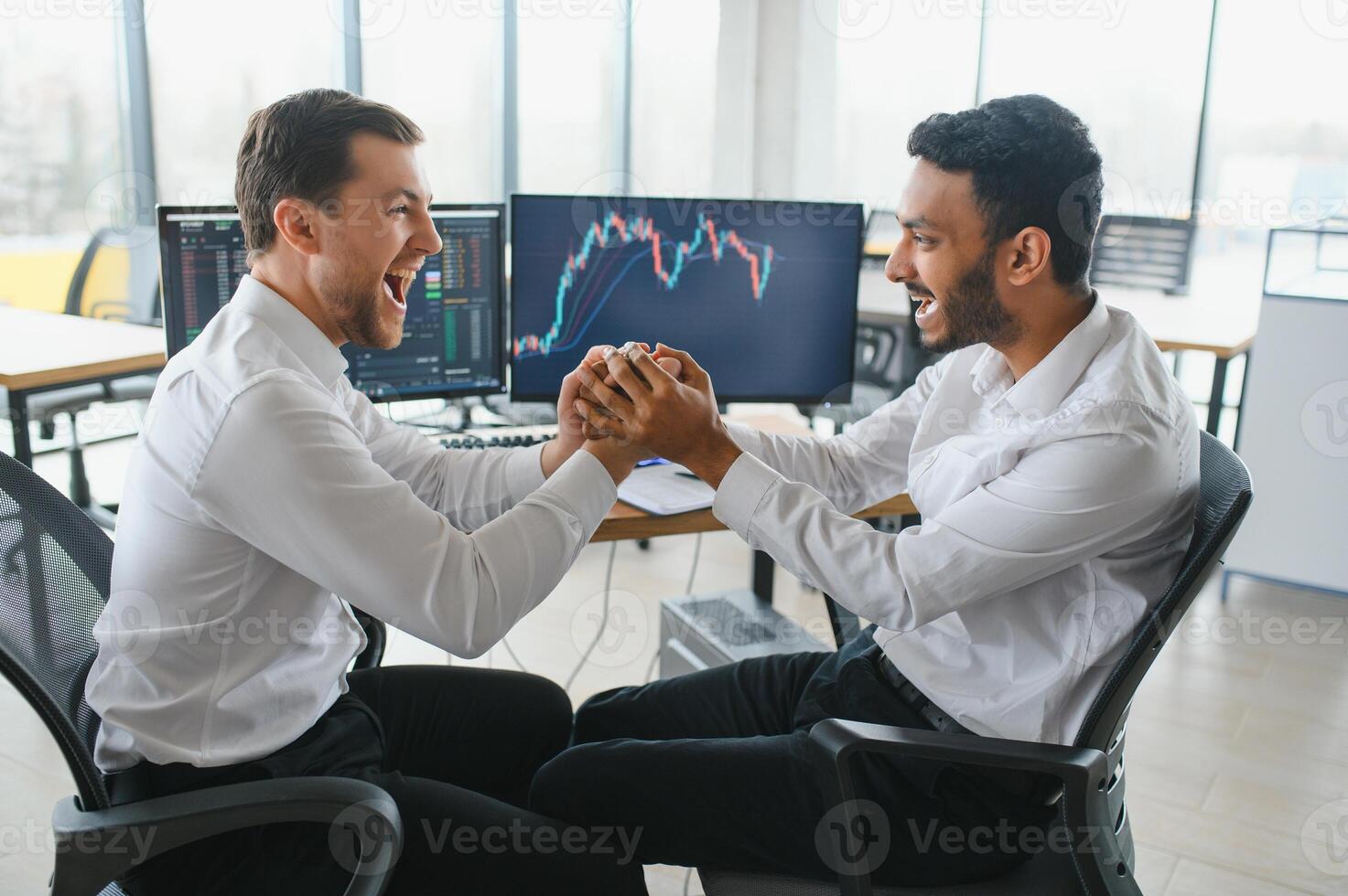 Two successful trader sitting in office and looking at screen, checking cryptocurrency information data on finance market graph, pointing on monitor photo