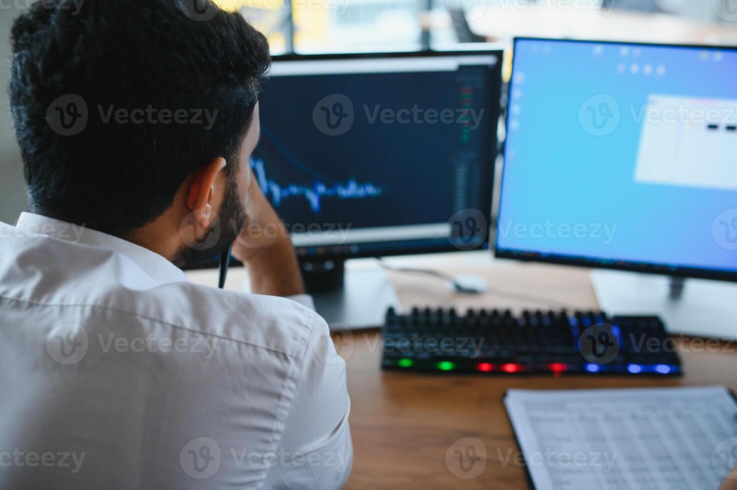 Thoughtful concentrated indian business man entrepreneur investor manager using computer, watching webinar working in office analyzing online data market thinking doing web research looking at laptop. photo