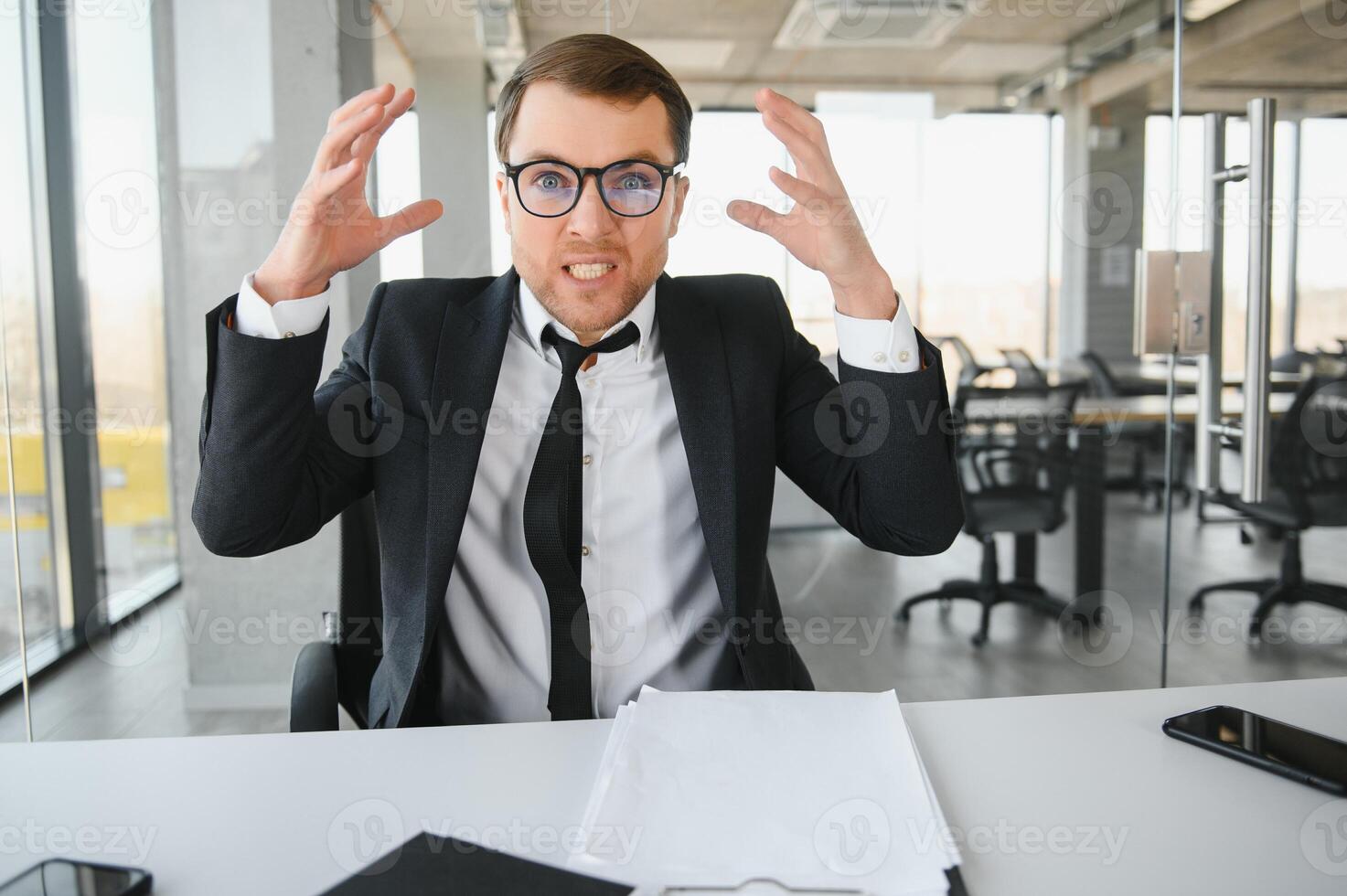 Angry businessman sitting at his desk and screaming at his employees. photo