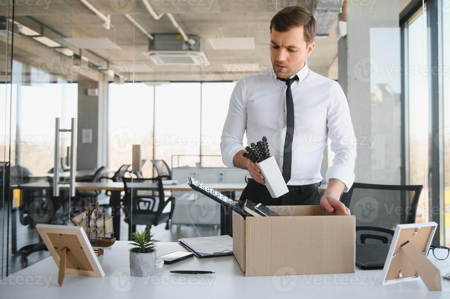 Fired young man packing his stuff in office photo