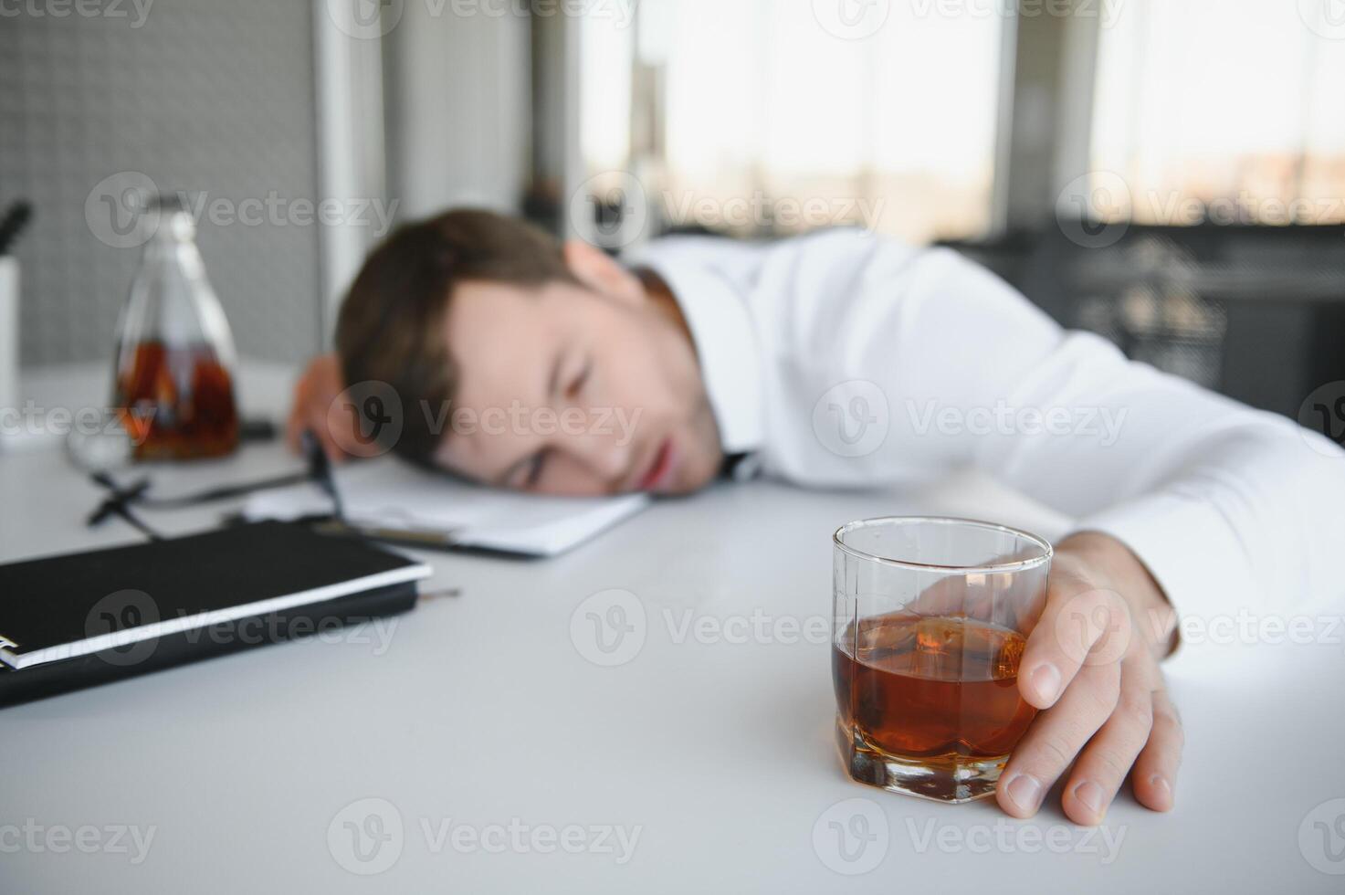 Alcoholism at work. Tired employee drinking alcohol at workplace, can not handle stress. photo
