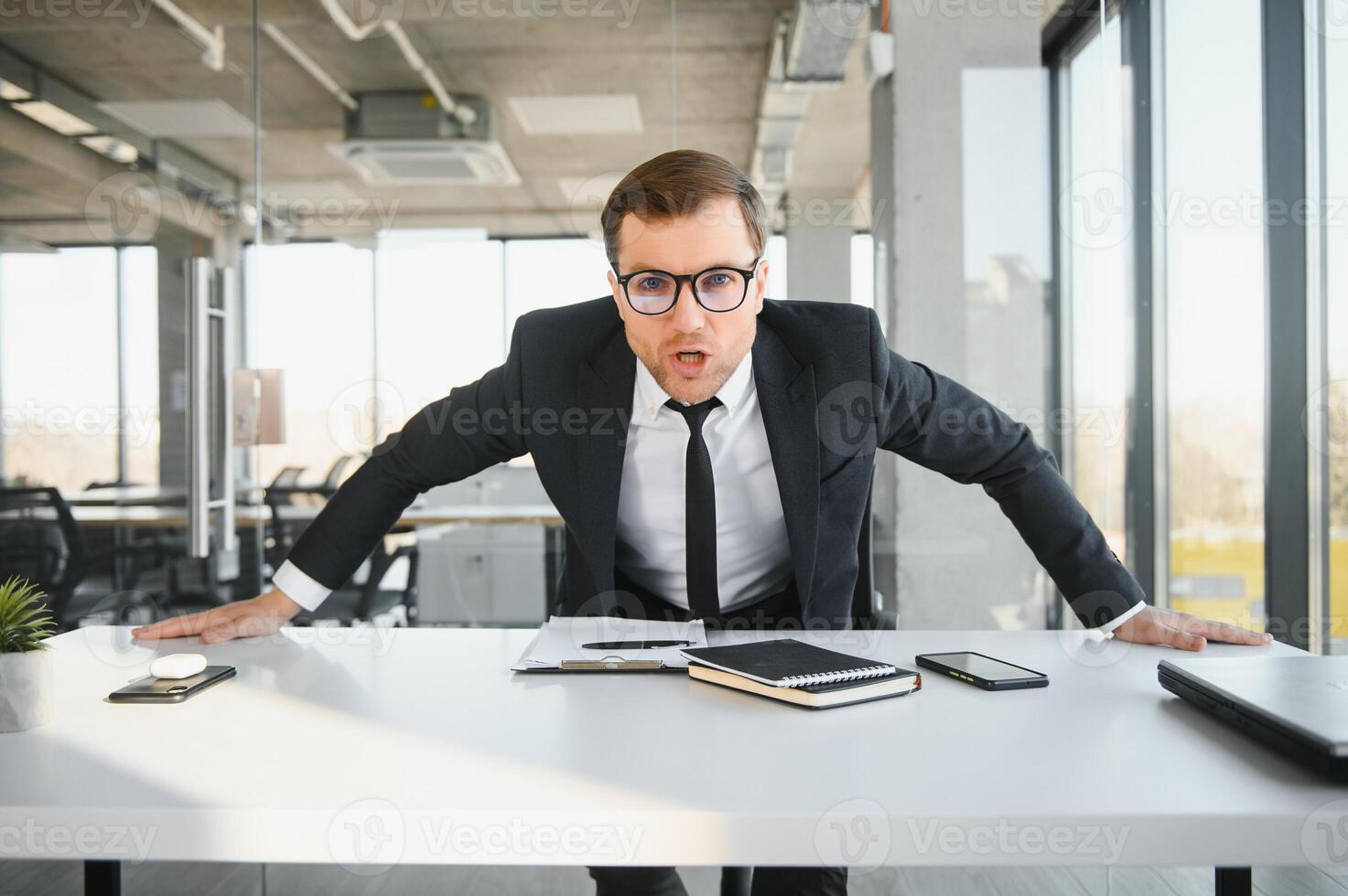 Angry senior businessman sitting at his desk and screaming photo