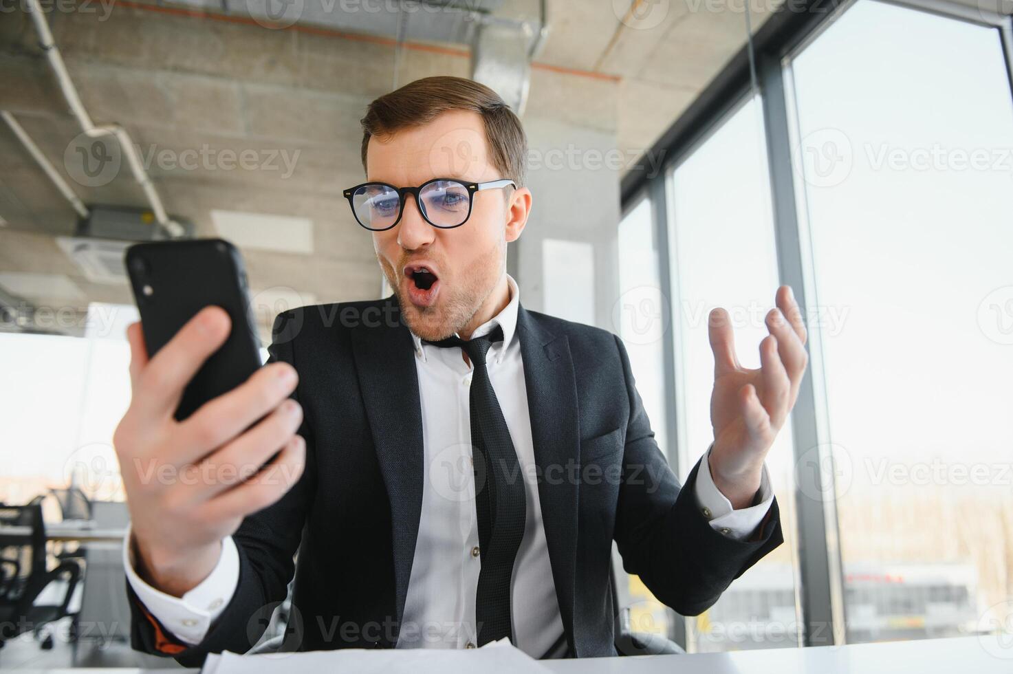 Angry senior businessman sitting at his desk and screaming photo