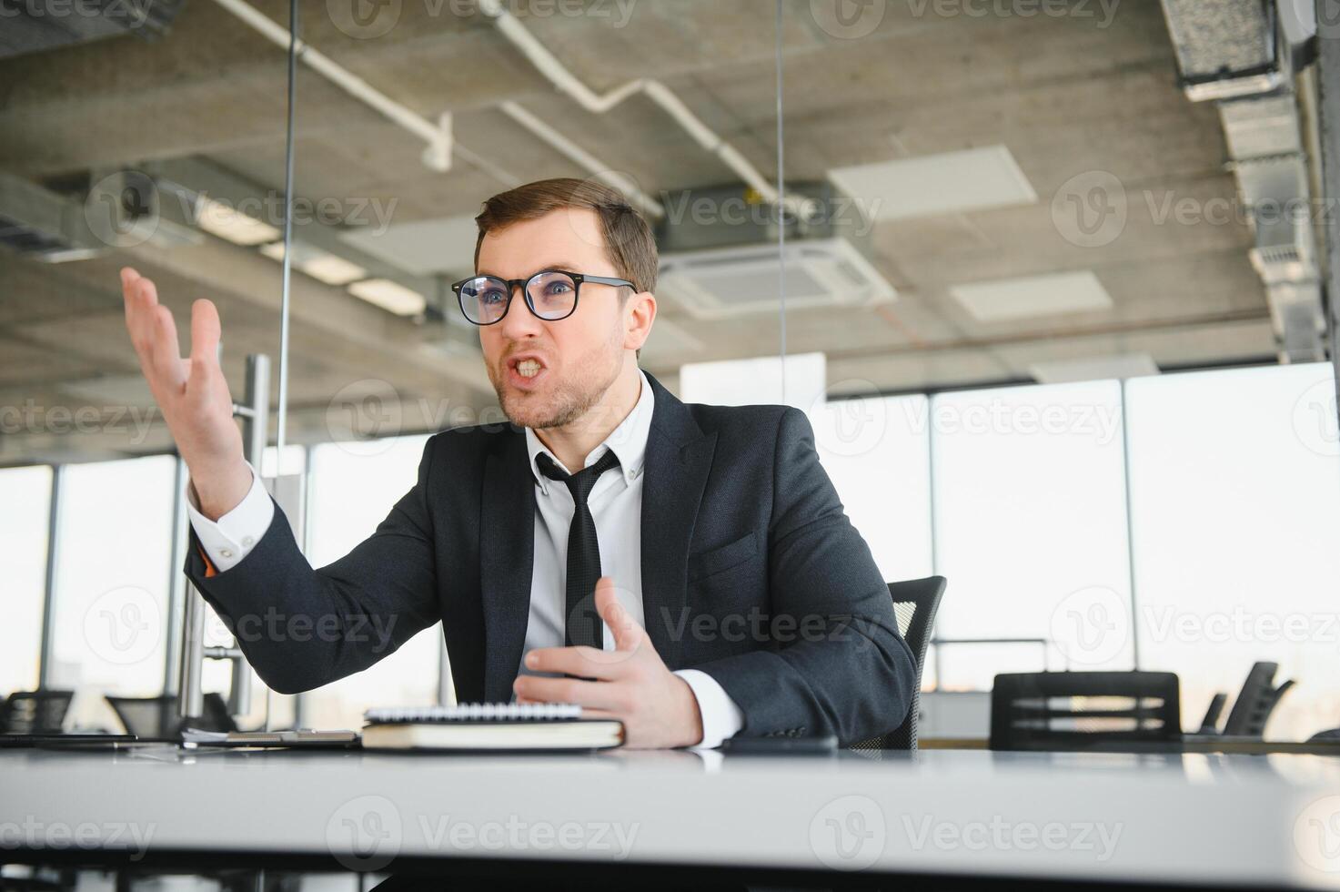 Angry businessman sitting at his desk and screaming at his employees. photo