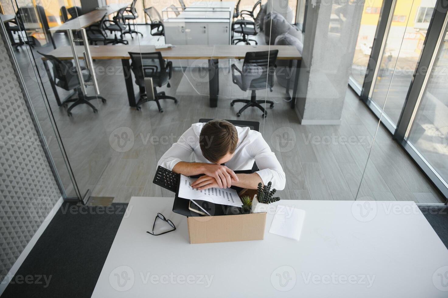 Sad Fired. Let Go Office Worker Packs His Belongings into Cardboard Box and Leaves Office. Workforce Reduction, Downsizing, Reorganization, Restructuring, Outsourcing. Mass Unemployment Market Crisis photo