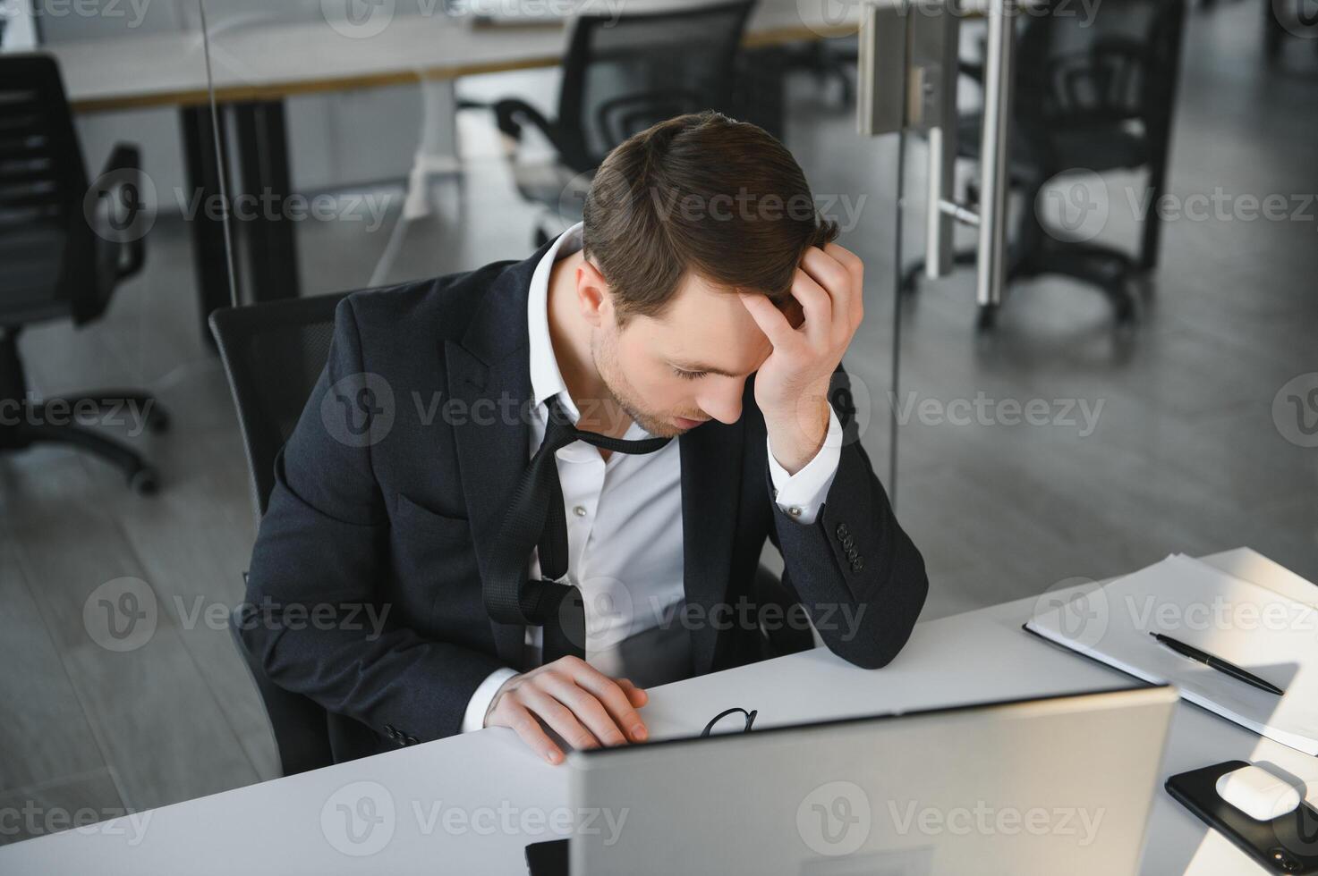 Focused serious businessman in suit thinking reading online news or solving business problem working on laptop looking at screen, worried puzzled executive managing stock market risks using computer photo