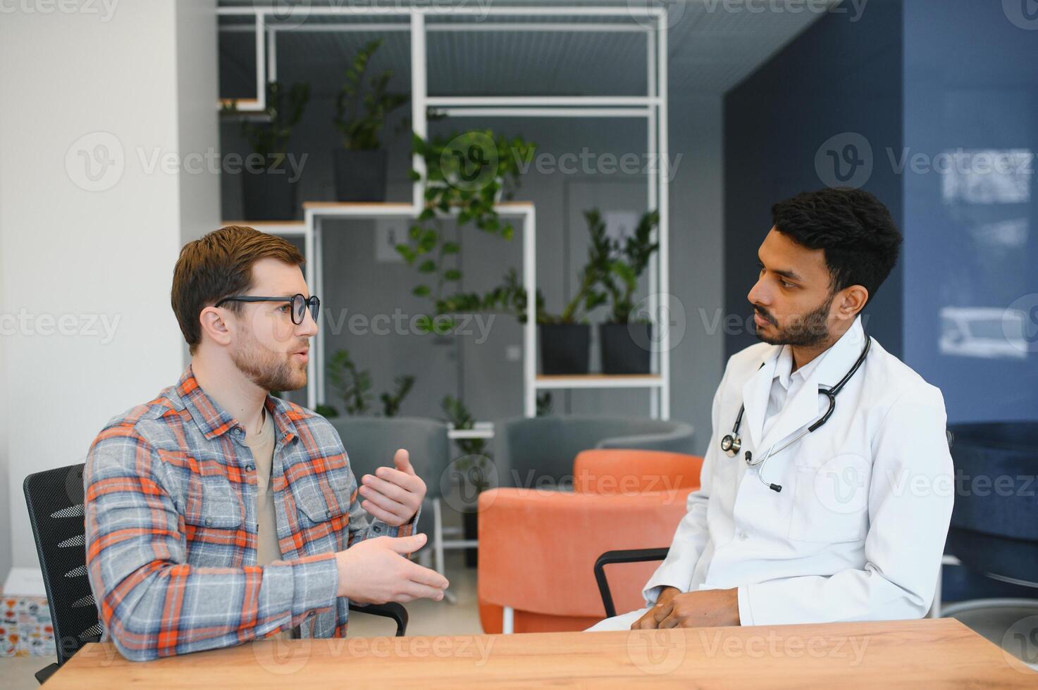 medicine, healthcare and people concept - indian doctor young male patient meeting at hospital photo