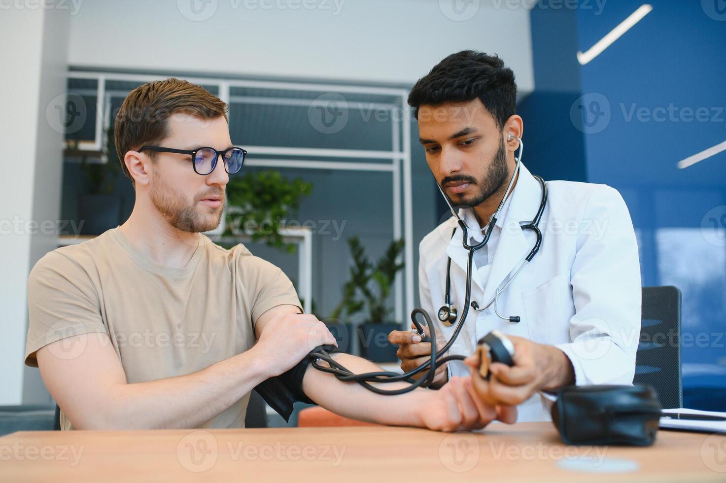 Indian Doctor Holding Dial While Measuring Man's Blood Pressure photo