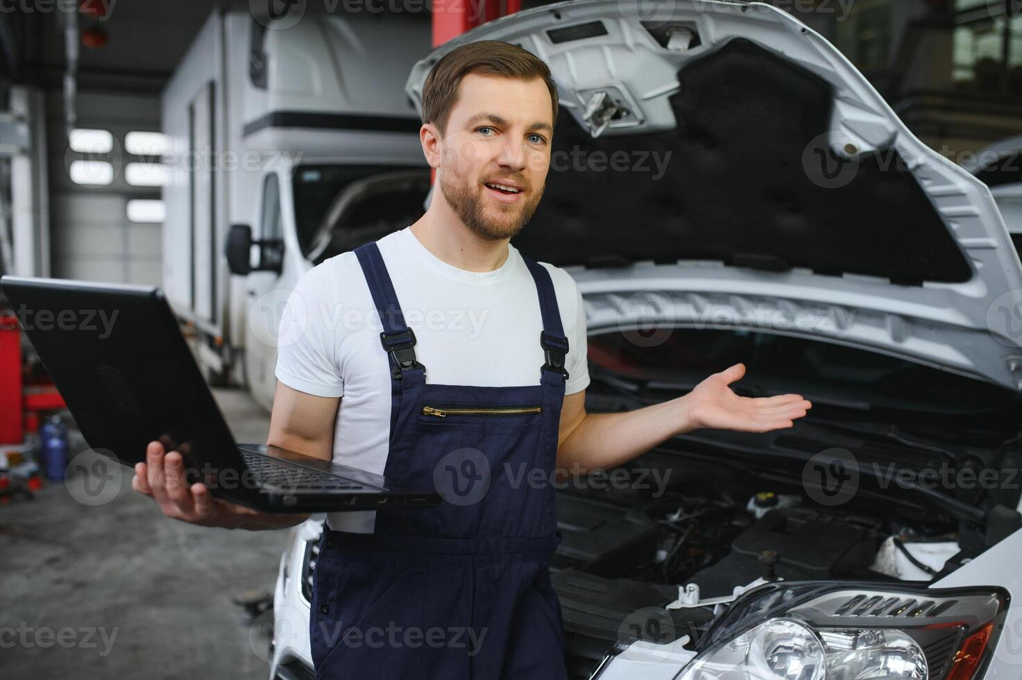 car mechanic using a computer laptop to diagnosing and checking up on car engines parts for fixing and repair photo