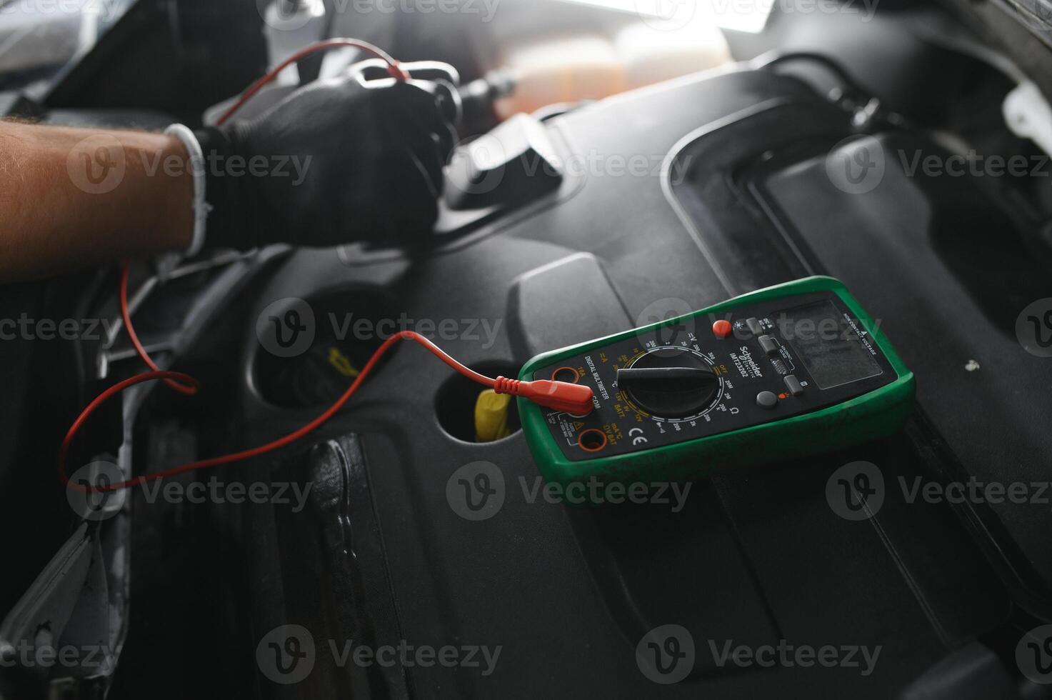 Car mechanic is using a multimeter with voltage range measurement to check the voltage level of the car battery. photo