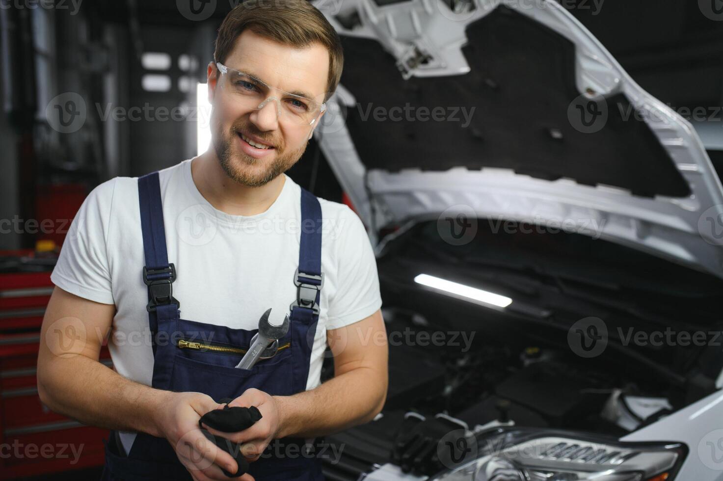 Portrait of a smiling fixing a car engine in his garage photo