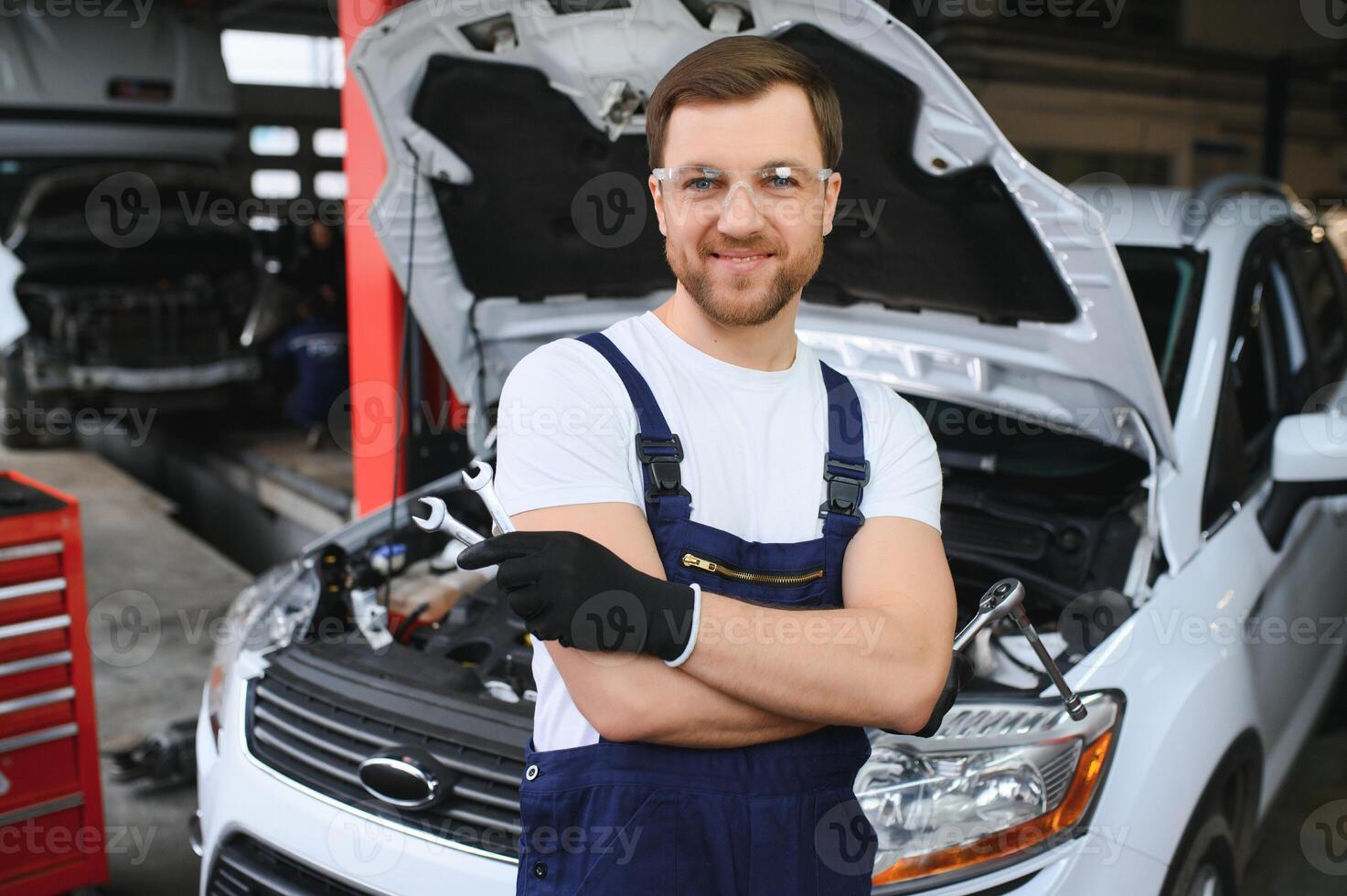 Portrait Shot of a Handsome Mechanic Working on a Vehicle in a Car Service. Modern Clean Workshop. photo