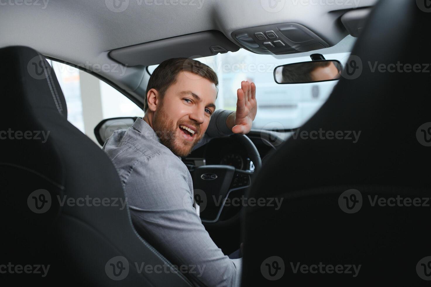 Young man is choosing a new vehicle in car dealership. photo