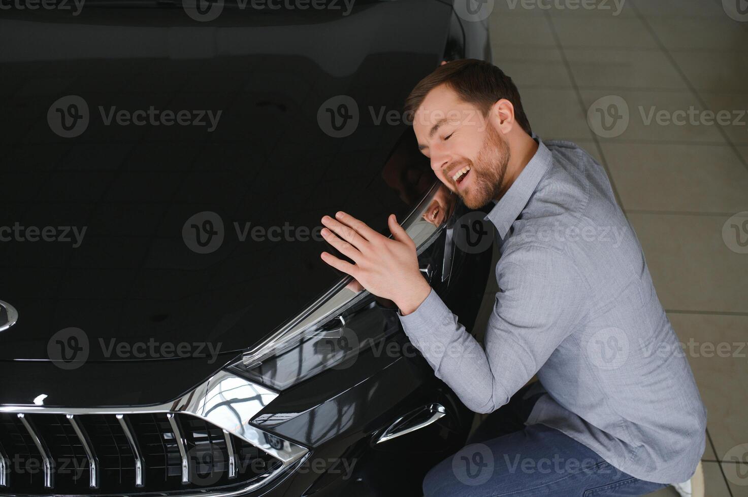 Visiting car dealership. Handsome bearded man is stroking his new car and smiling photo