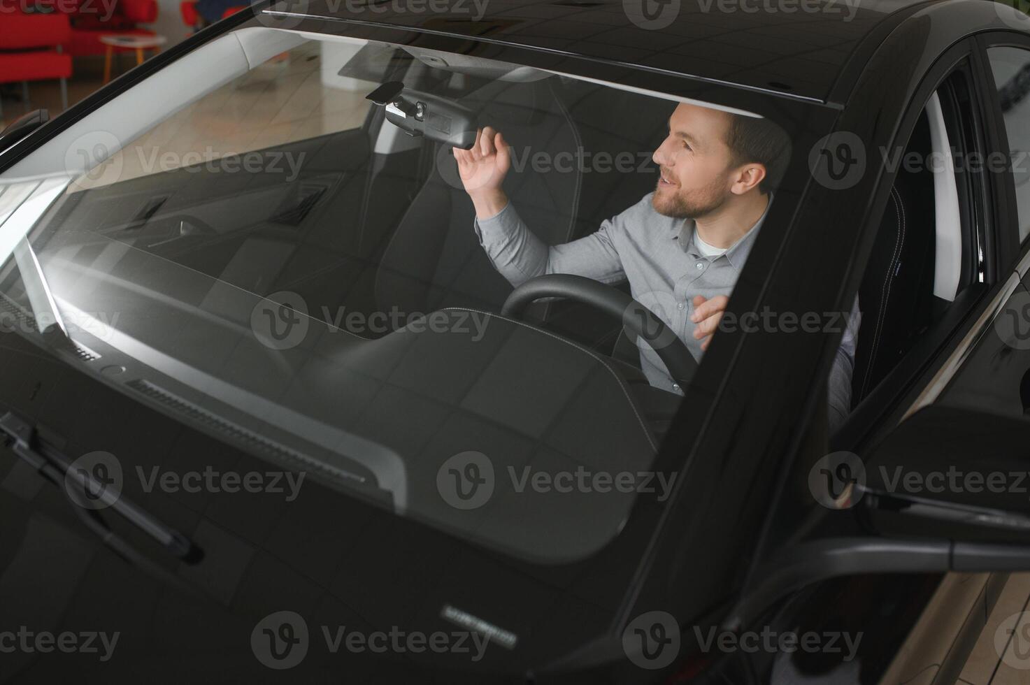 Happy young driver behind the wheel inside new car. Lifestyle scene in the car dealership photo