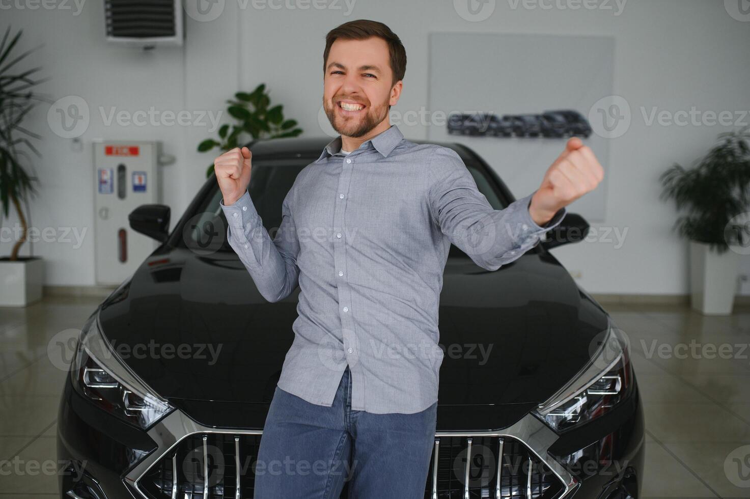Visiting car dealership. Handsome bearded man is stroking his new car and smiling. photo
