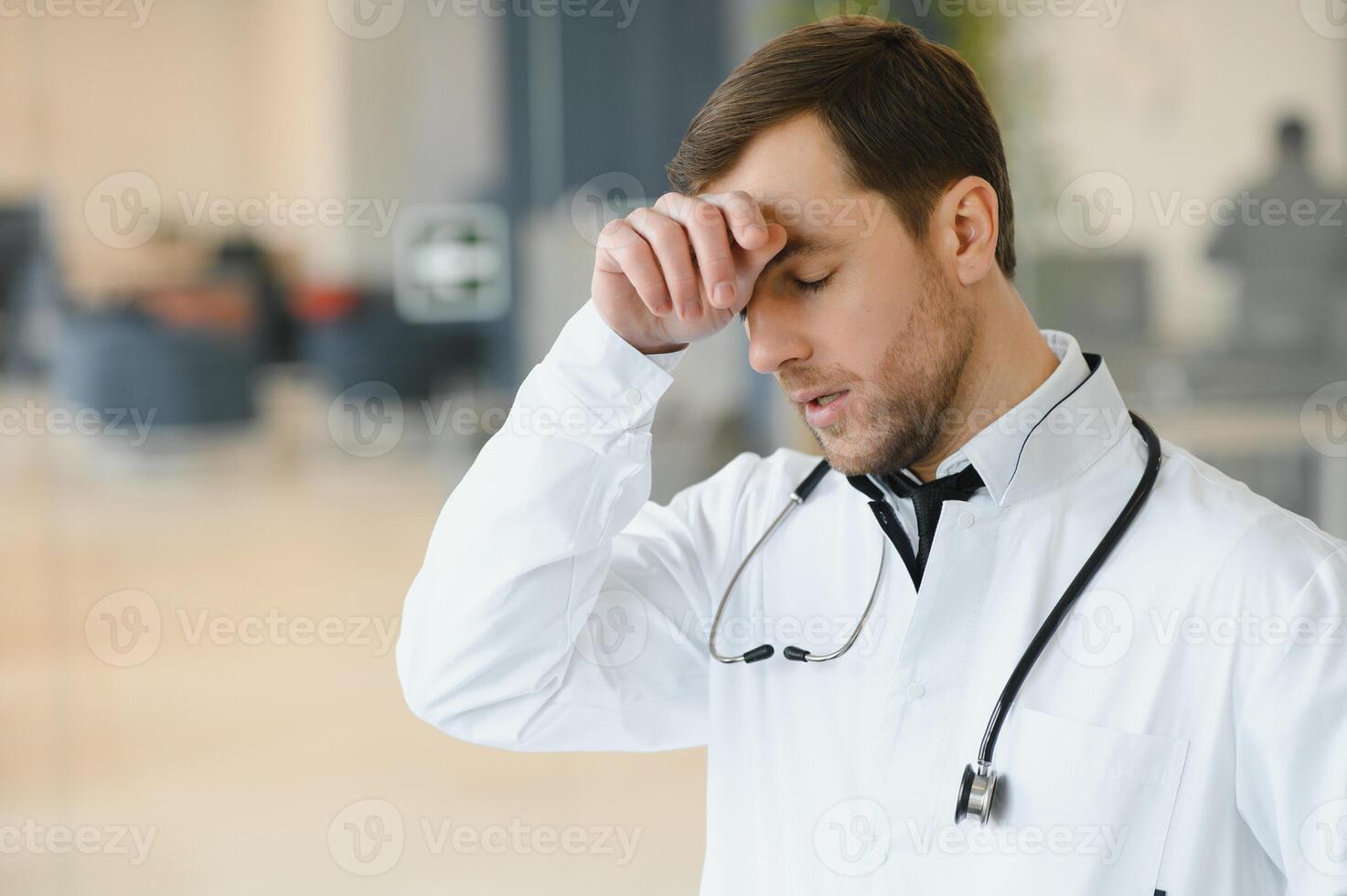 Stressed male doctor. Mid adult male doctor working long hours. Overworked doctor in his office. Not even doctors are exempt from burnout . photo