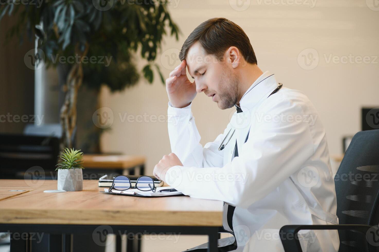 Young man wearing doctor uniform stressed working at clinic photo