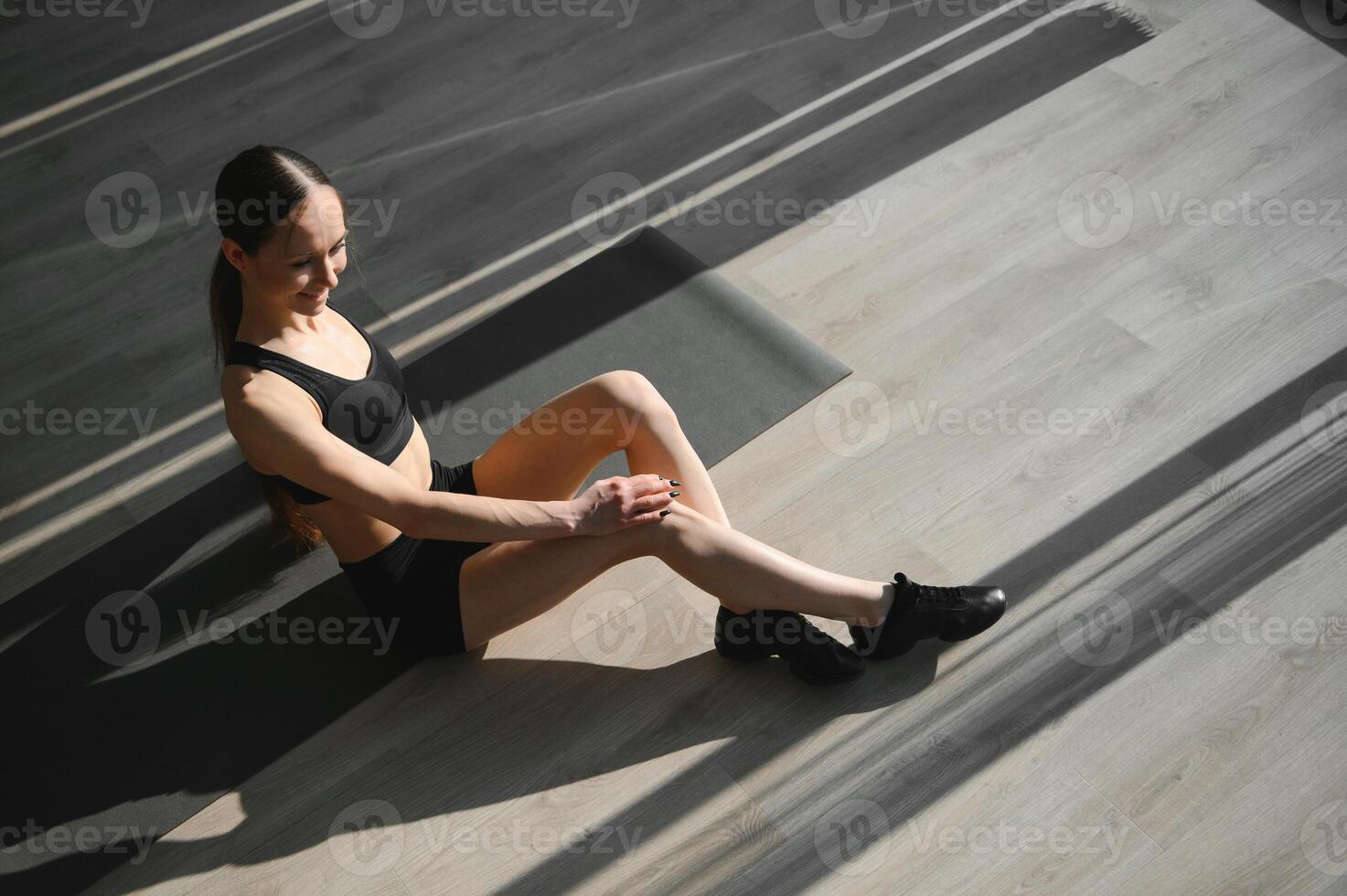 Young attractive sporty woman sitting on mat at gym photo