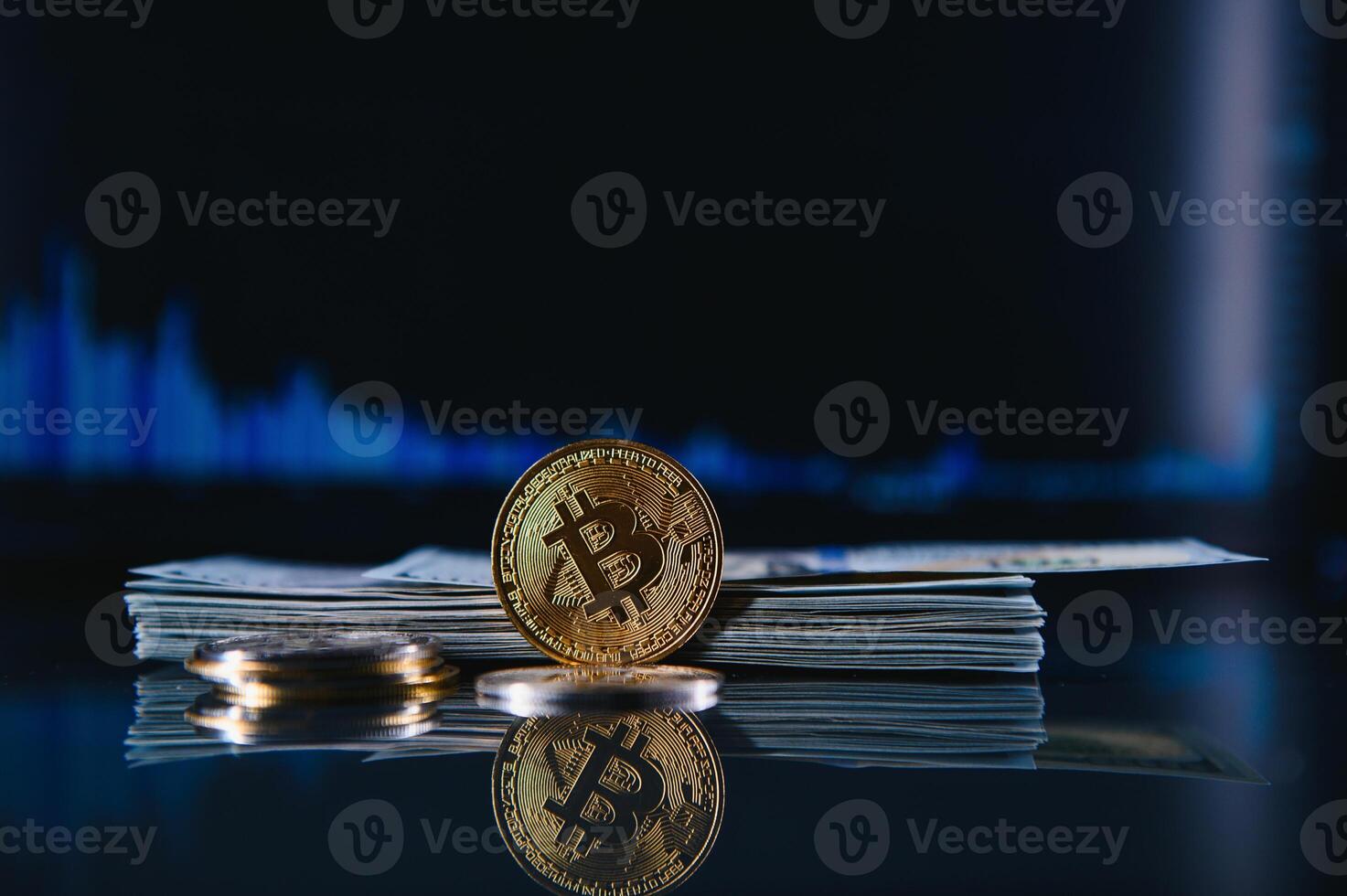 Golden bitcoin are stacked on a bright background of business graphs close-up. Bitcoin cryptocurrency. Folded in a tube 100 dollar bills photo