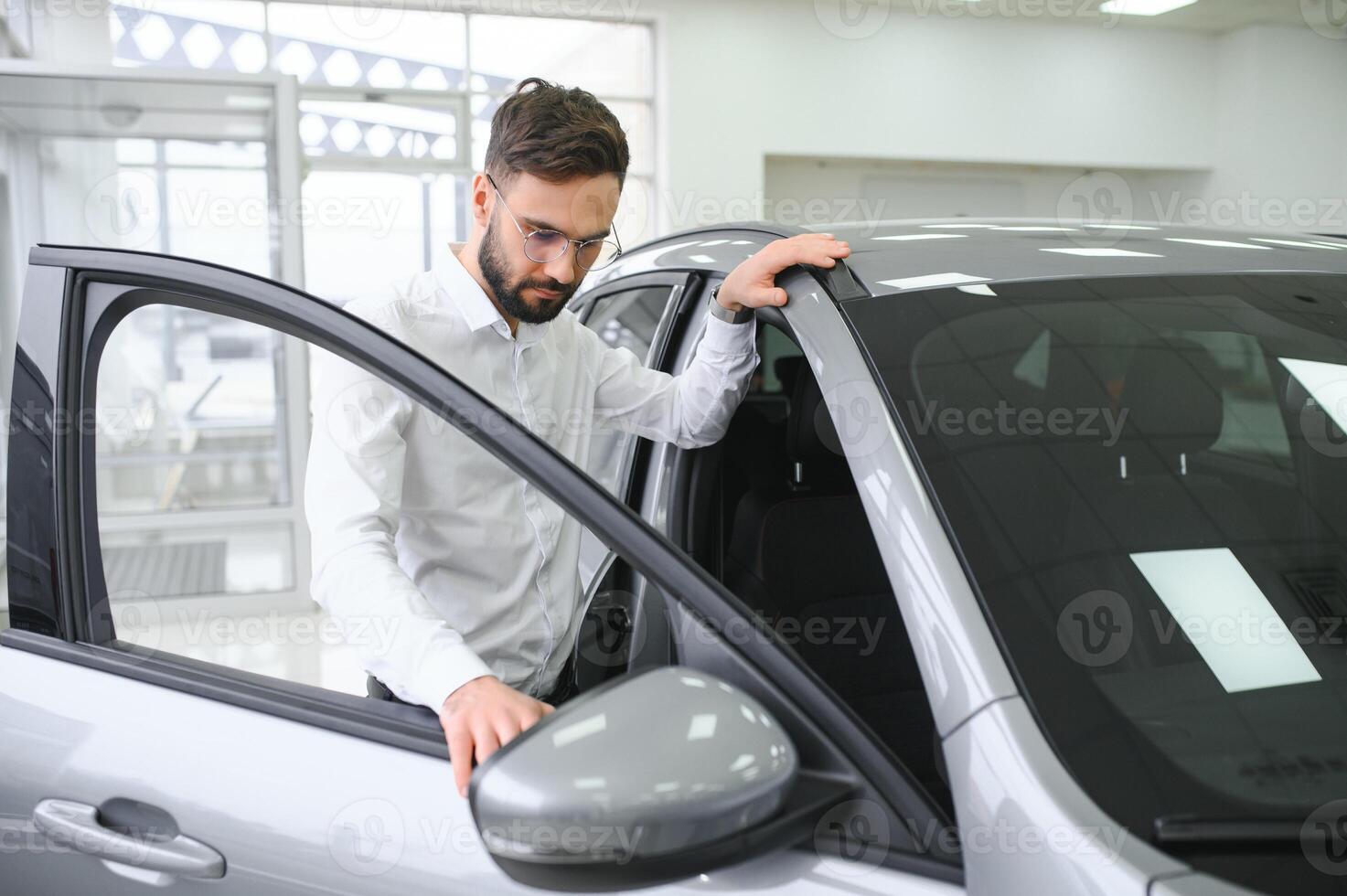 a man examines a car in a car dealership photo