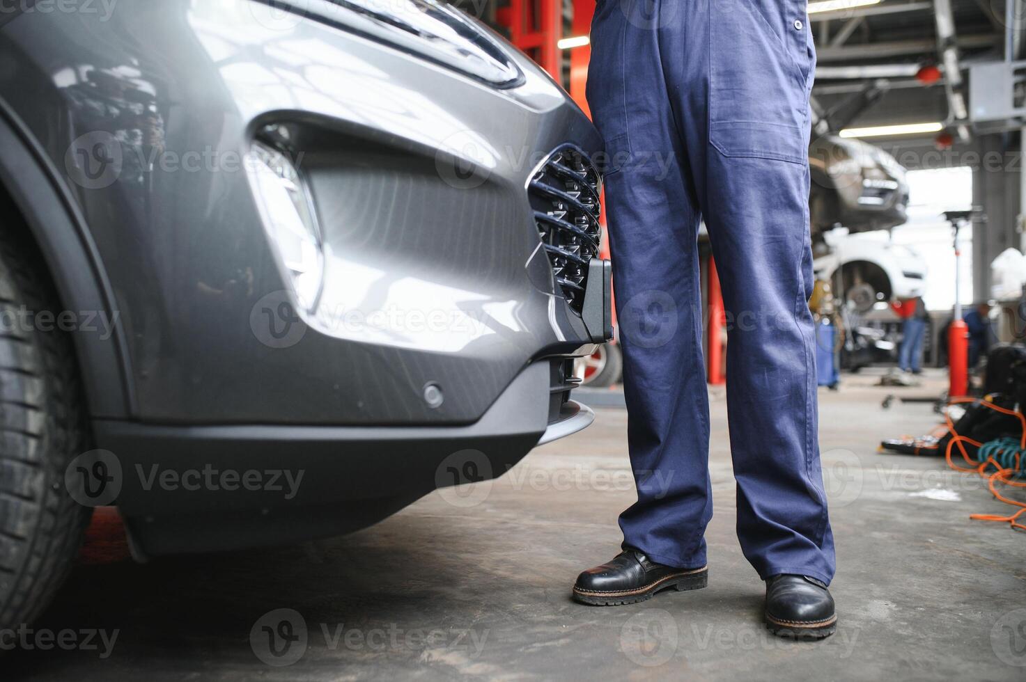 Mechanic examining under hood of car at the repair garage photo