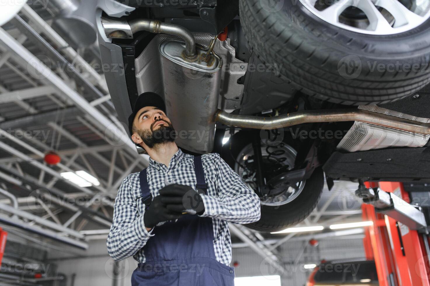 Portrait of a mechanic repairing a lifted car photo
