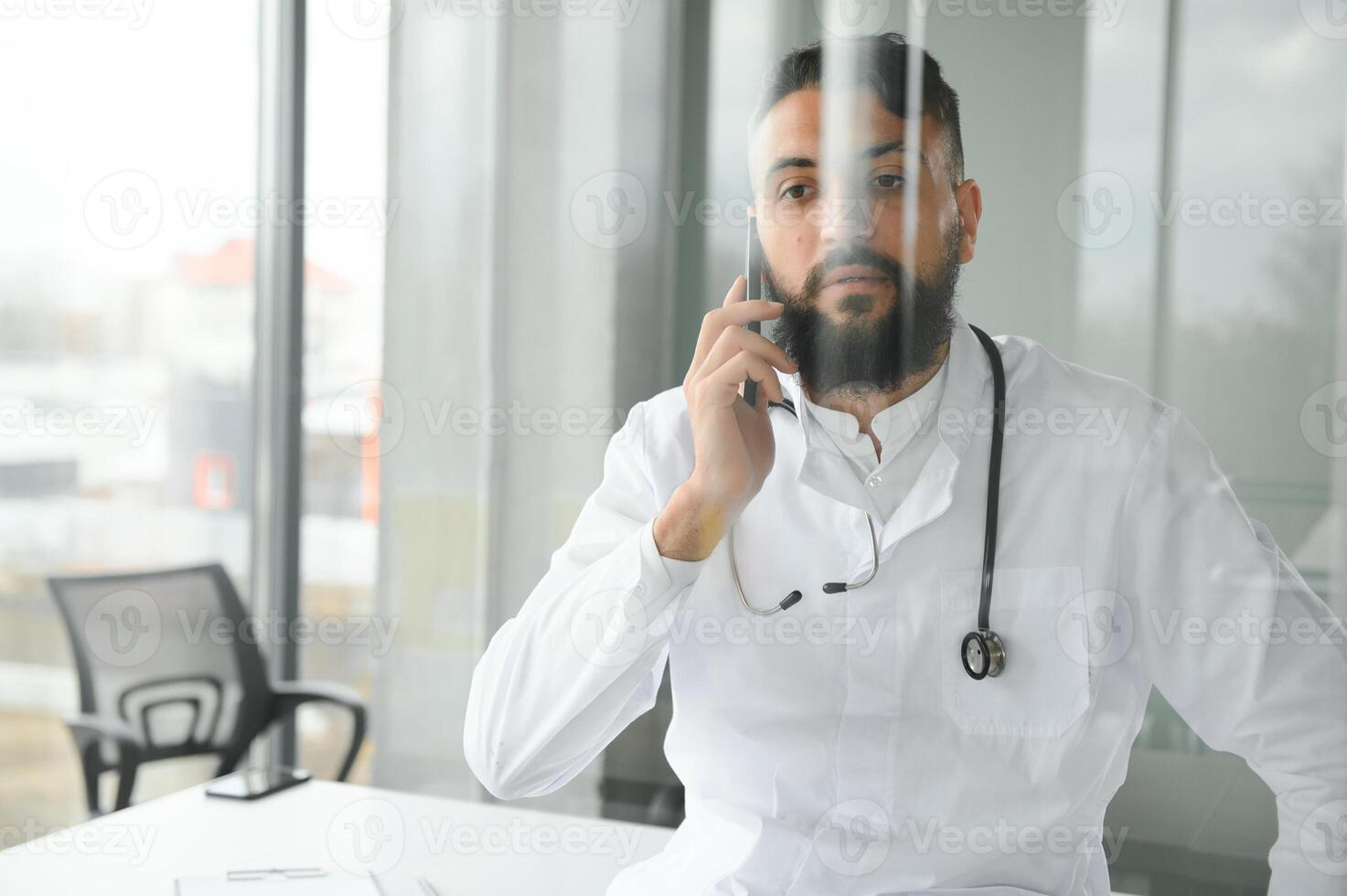 Portrait of pleasant young Arabian doctor in white coat. photo