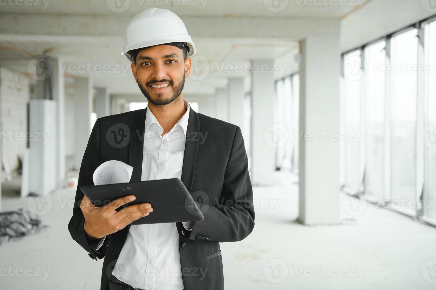 Confident asian engineer man Using tablet for checking and maintenance to inspection at modern home building construction. Architect working with white safety helmet in construction site. photo
