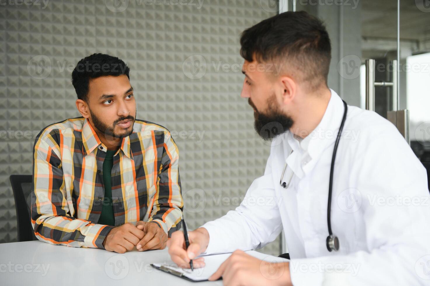 medicine, healthcare and people concept - happy doctor with clipboard and young male patient meeting at hospital photo