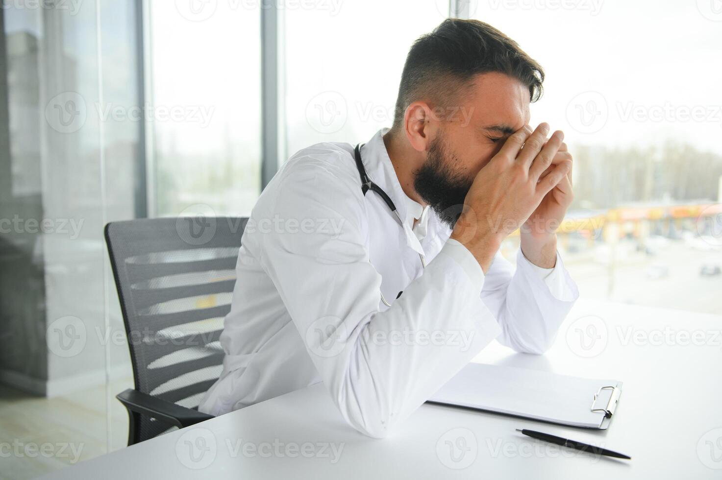 Portrait of exhausted tired young arab male doctor after hard day at work photo