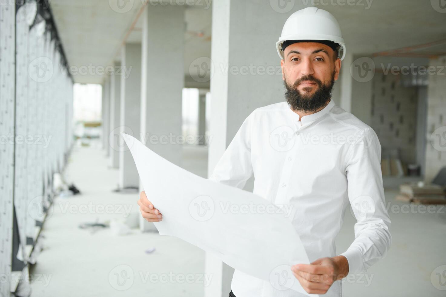 Young attractive arabic industrial engineer in hard hat. Professional and industry, builder architect job, worker checking work at plant indoor photo