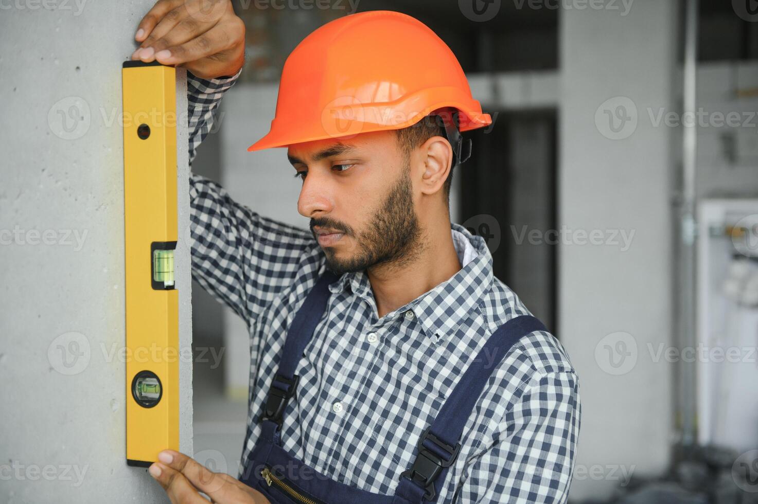 Indian construction site manager standing wearing helmet, thinking at construction site. Portrait of mixed race manual worker or architect. photo