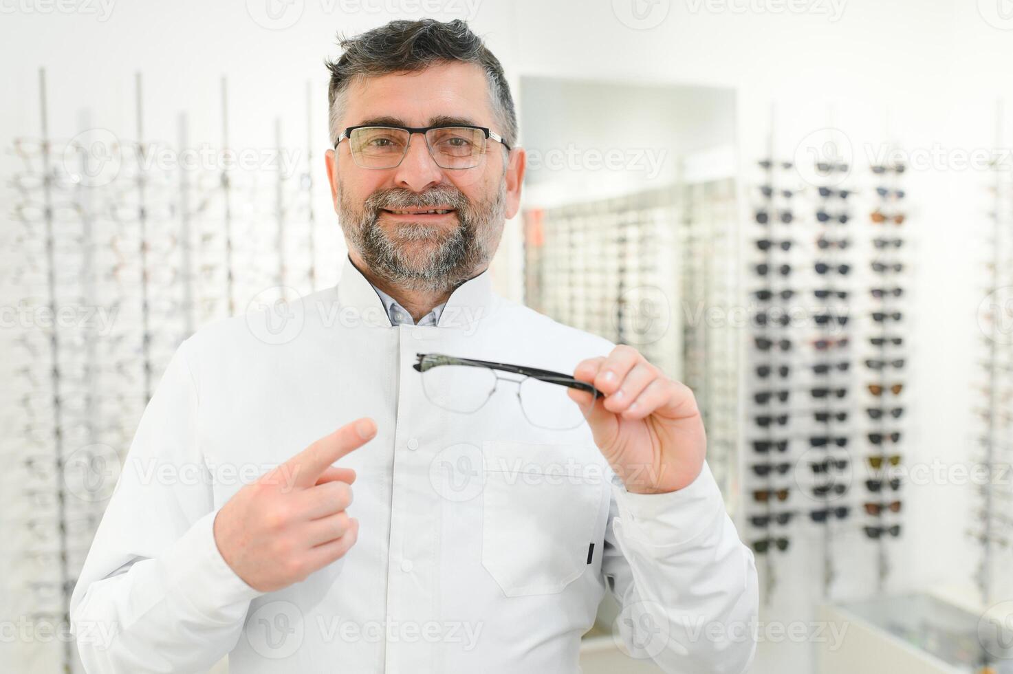 Handsome ophthalmologist holding eyeglasses for a try out. Optometrist offering to wear a pair of glasses. Image with small deph of field focused on the hands and glasses photo