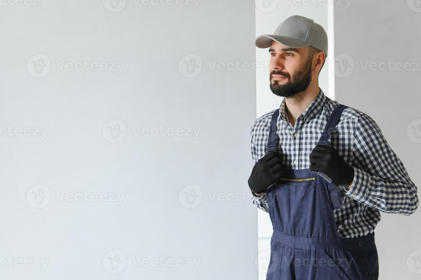 Portrait of handsome mechanic with stubble in blue overall, shirt having his arms crossed, looking at camera photo