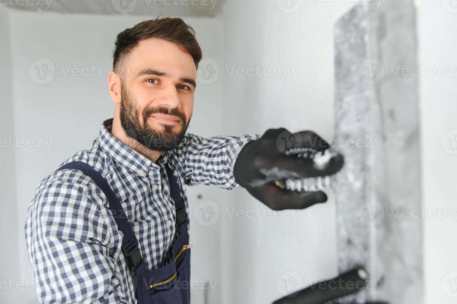 Portrait of handsome mechanic with stubble in blue overall, shirt having his arms crossed, looking at camera photo
