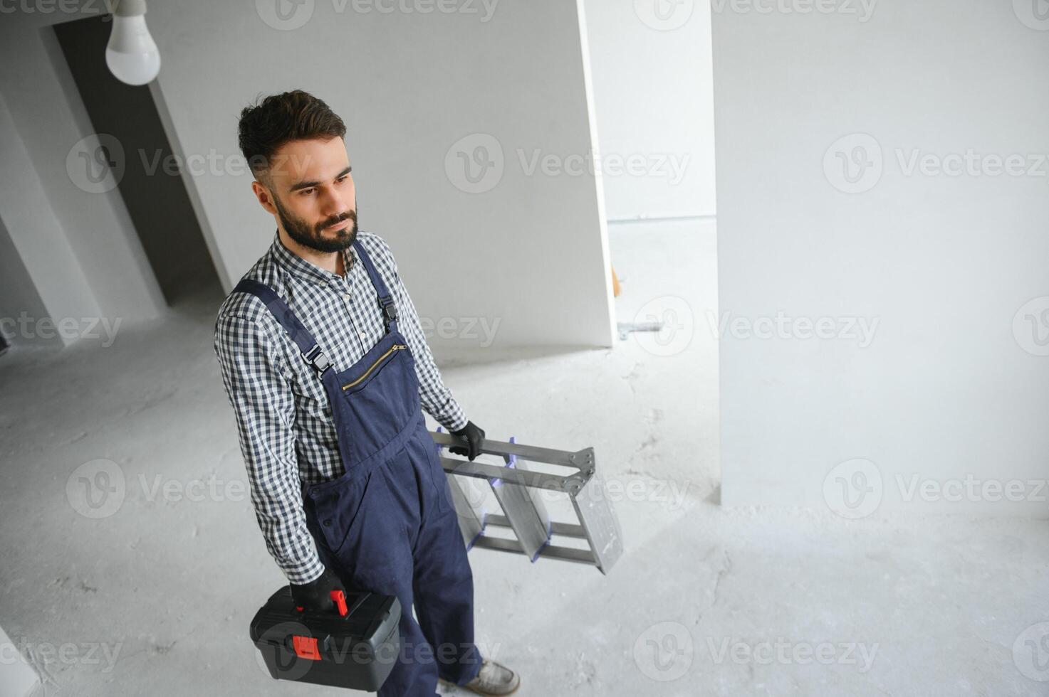 Laughing construction worker on the background of a gray concrete wall. Renovation. place for text photo