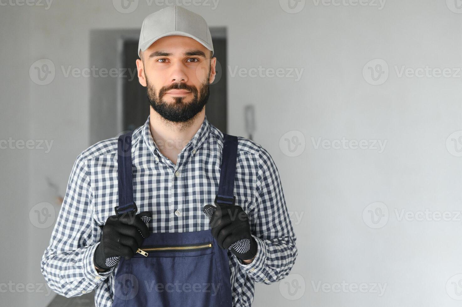 Laughing construction worker on the background of a gray concrete wall. Renovation. place for text photo