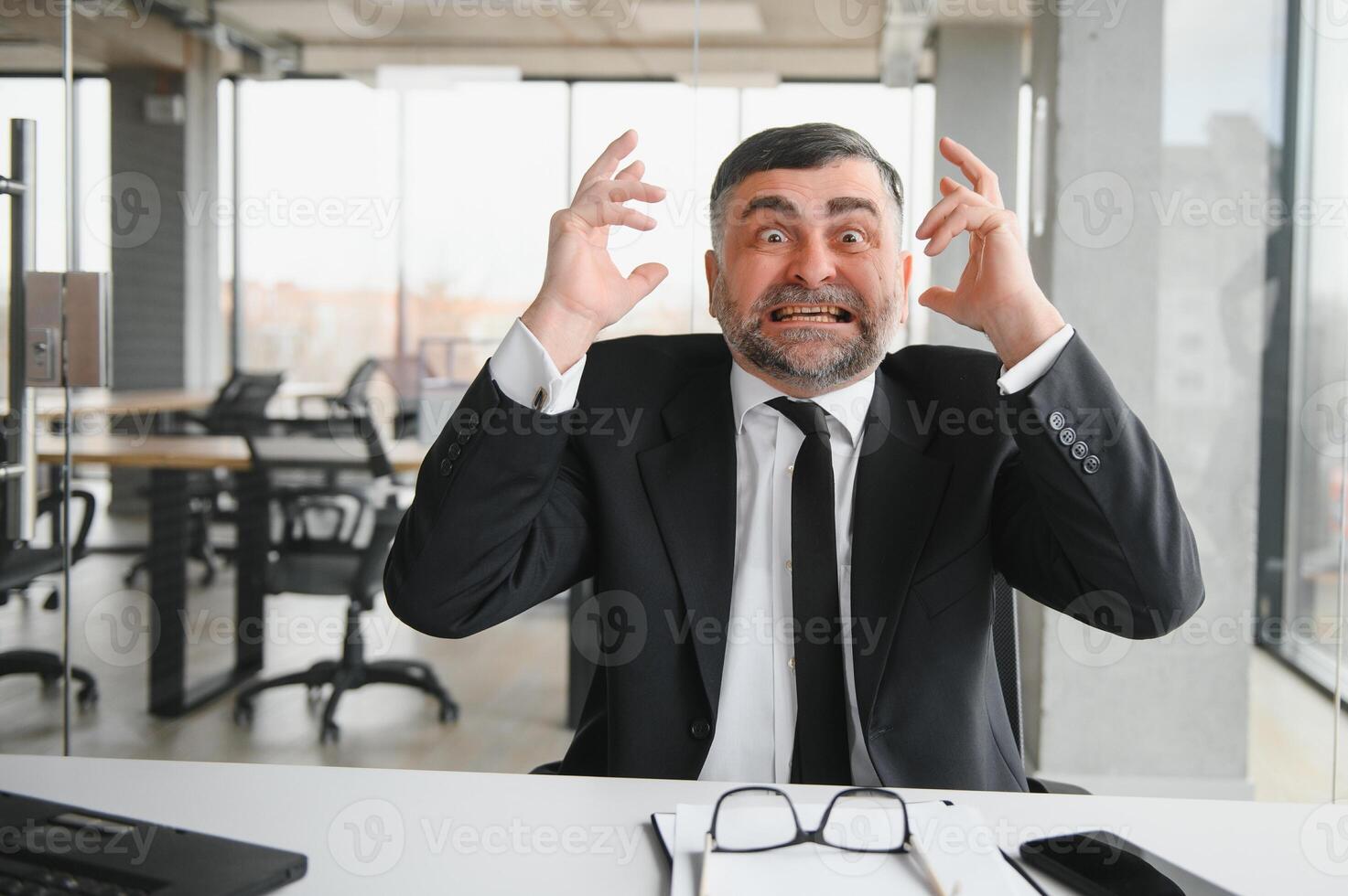 Angry businessman sitting at the table and screaming over. photo