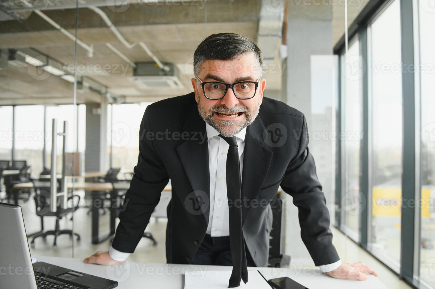 Angry boss behind of office table photo