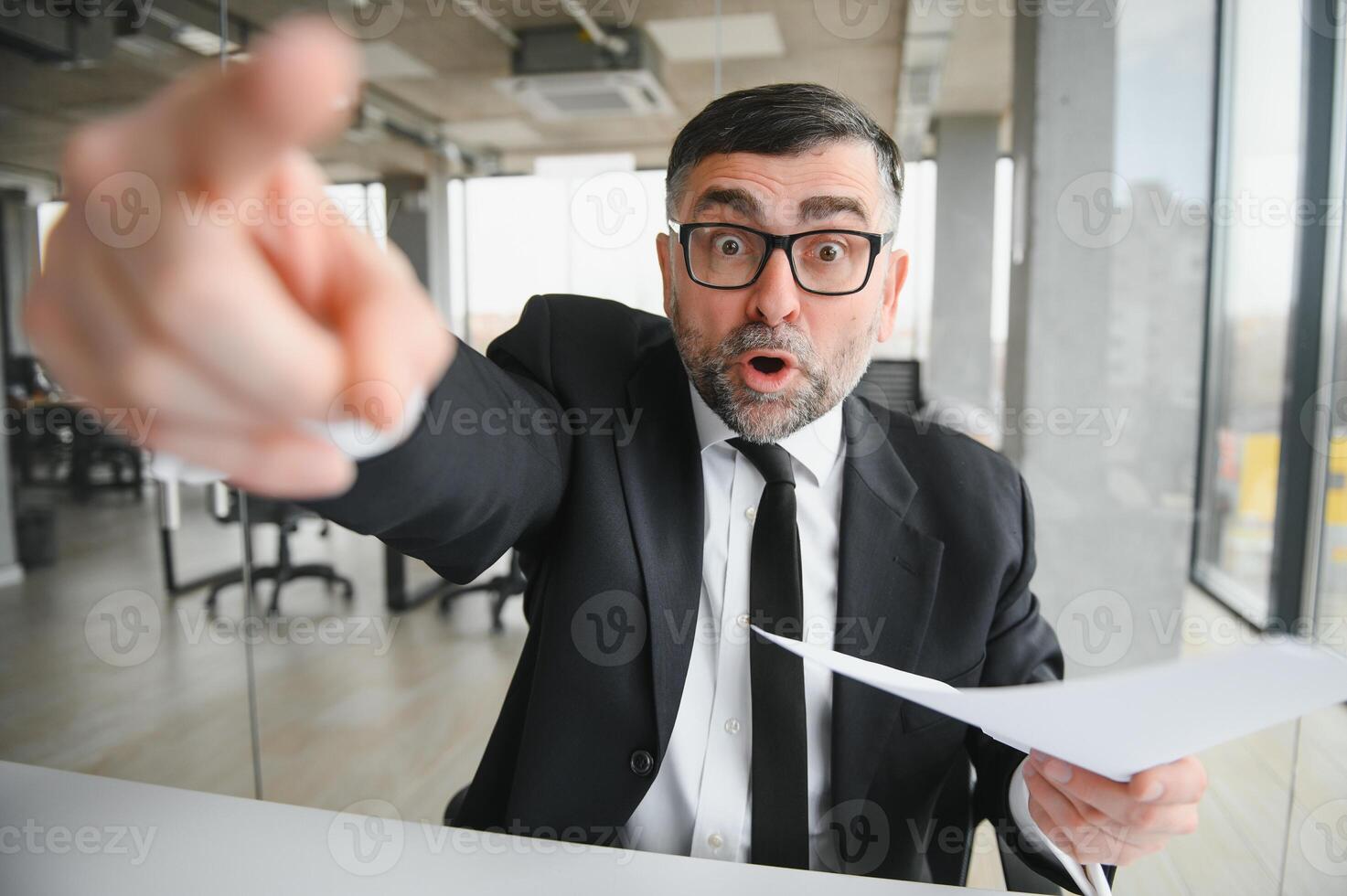 Angry businessman sitting at the table and screaming over. photo