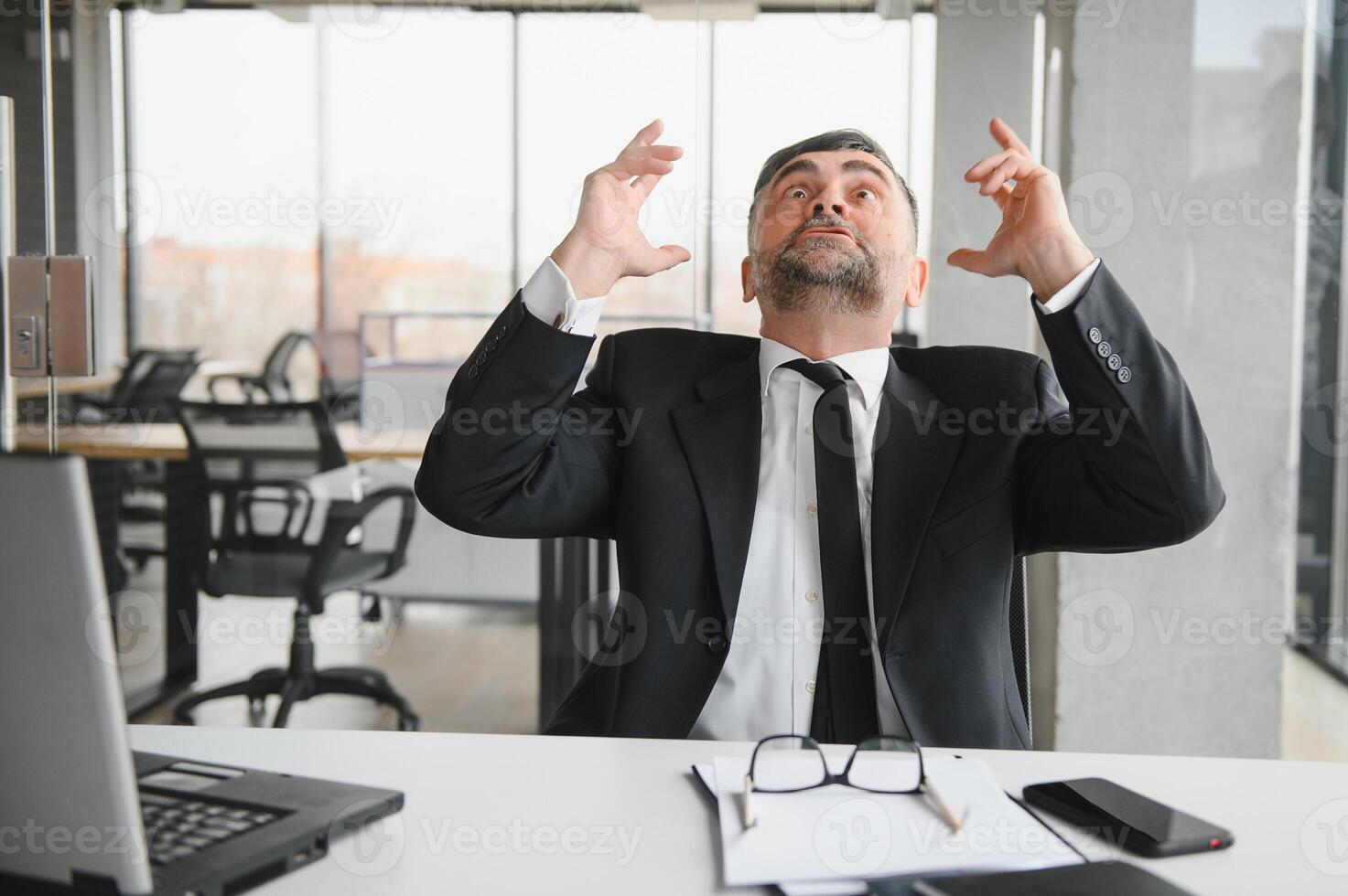 Angry businessman sitting at the table and screaming over. photo